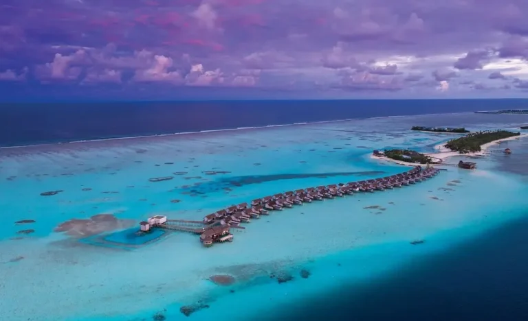 Aerial view of overwater villas over a turquoise lagoon at OZEN LIFE Maadhoo, South MalΓ© Atoll