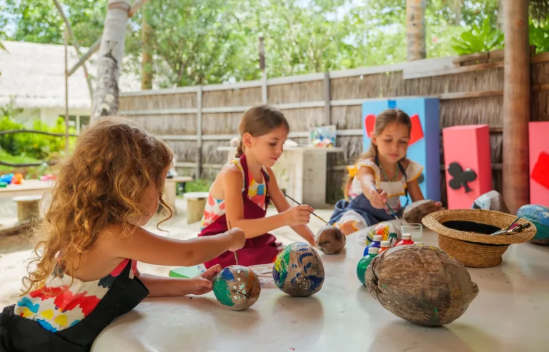 Children painting coconuts at a craft table at the Sultan's Village Kids Club, Amilla Maldives
