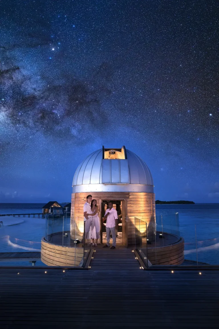 Couple at an overwater observatory dome under a starry night sky at SKY, Anantara Kihavah, Maldives