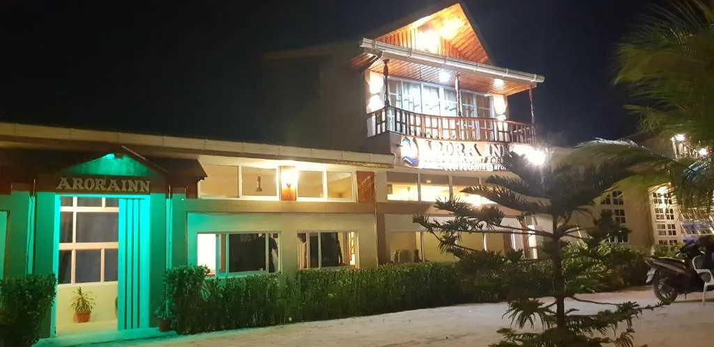 Two-story beachfront inn lit up at night with a tropical garden at Arora Inn, Maafushi, Maldives