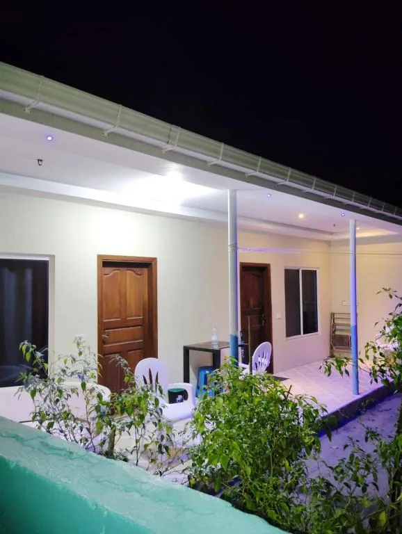 Single-story bungalow with wooden doors, covered veranda with plastic chairs, small table and blue LED strip lighting at Aurora Dhangethi, Dhangethi, Maldives