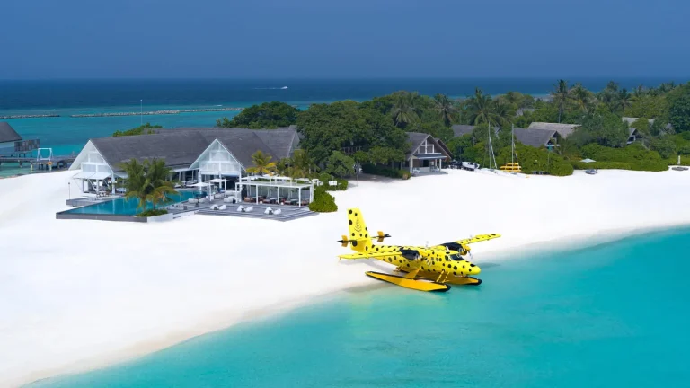 Yellow seaplane on the white sand shore in front of a beach villa at Four Seasons Resort Maldives at Landaa Giraavaru, Baa Atoll