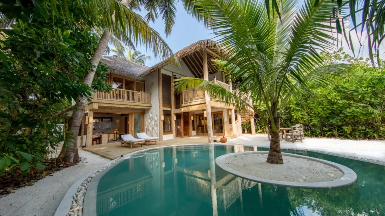 Two-bedroom Crusoe Residence at Soneva Fushi with a wooden two-storey villa, palm tree and curved private pool among thick jungle, Baa Atoll