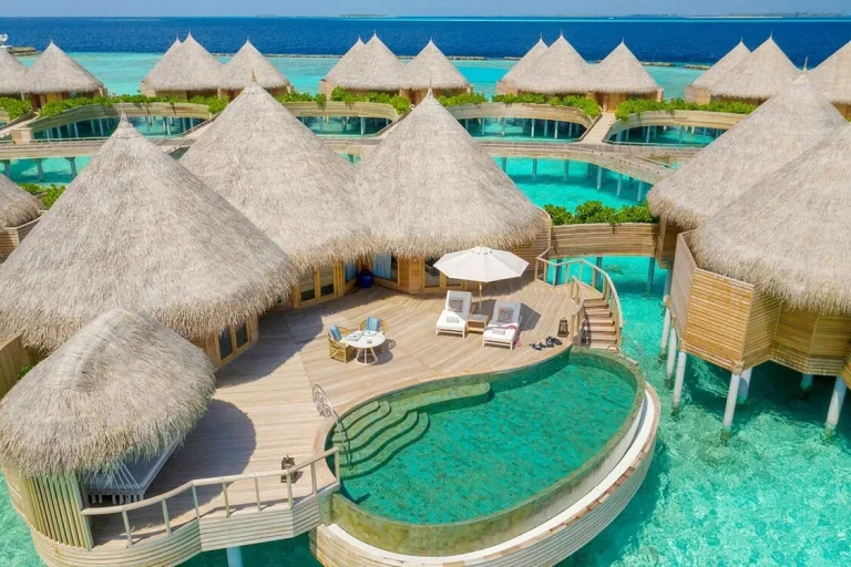 Thatched overwater Ocean House at The Nautilus Maldives with a round private pool, loungers and sun umbrella above a turquoise lagoon, Baa Atoll