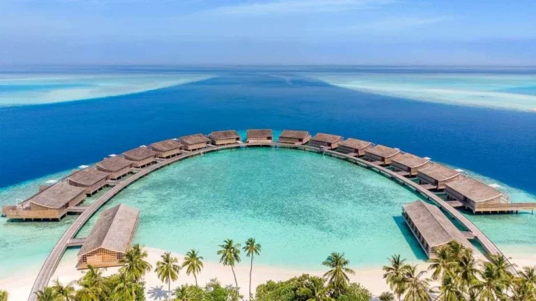 Aerial view of the Kudadoo Ocean Residences in a semicircle on stilts around a turquoise lagoon, Lhaviyani Atoll, Maldives