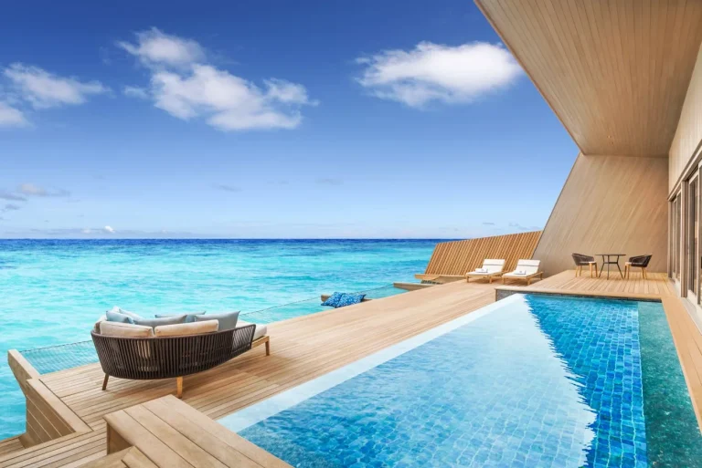 Overwater villa deck with a long blue-tiled private pool and lounge seating above the open sea at The St. Regis Maldives Vommuli Resort, Dhaalu Atoll