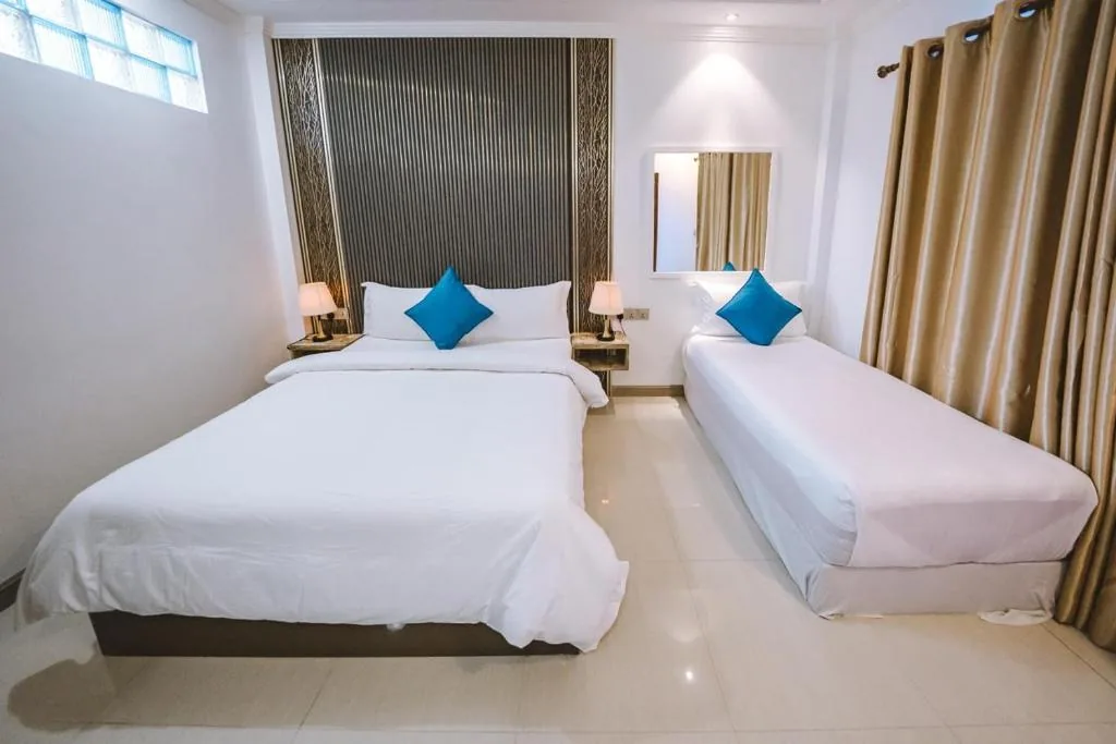 Room with a double and single bed, blue accents and a full-length mirror at Bliss Haven, Maafushi, Maldives