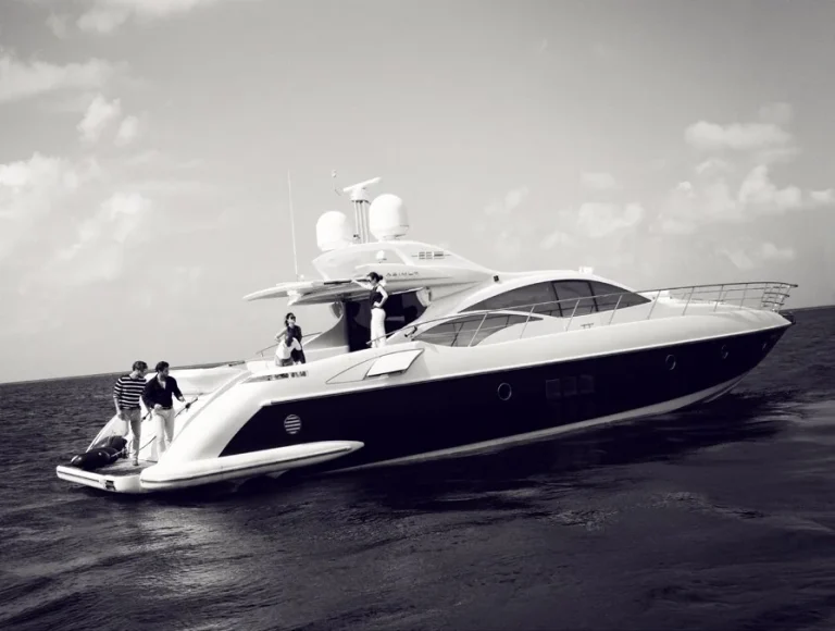 Black and white photo of a luxury motor yacht with guests on deck at sea, Coco Privé Kuda Hithi, Maldives