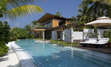 Modern timber residence with sun loungers beside a long pool among palms, Coco Privé Kuda Hithi, Maldives