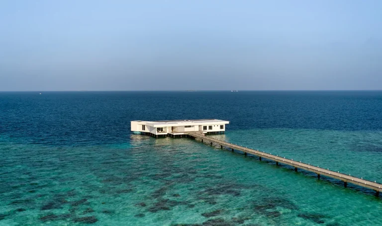 Small white pavilion at the end of a long jetty over a shallow reef, the entrance to Ithaa Undersea Restaurant, Conrad Maldives Rangali Island