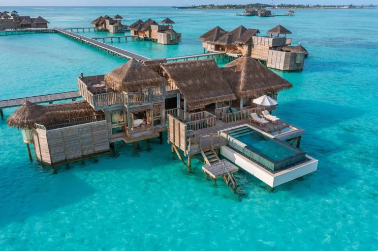Two-storey thatched overwater villa with a rooftop terrace, deck and private pool above clear water at Gili Lankanfushi