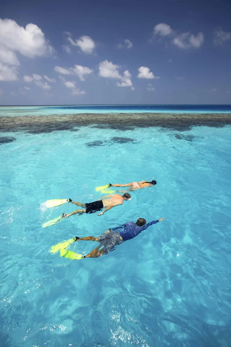 Two snorkellers floating over a reef in clear shallow water near Gili Lankanfushi, Maldives