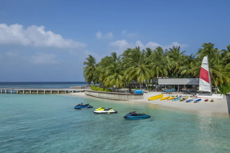 Beach with jet skis, kayaks and a catamaran at the watersports centre of The Halcyon Private Isles Maldives