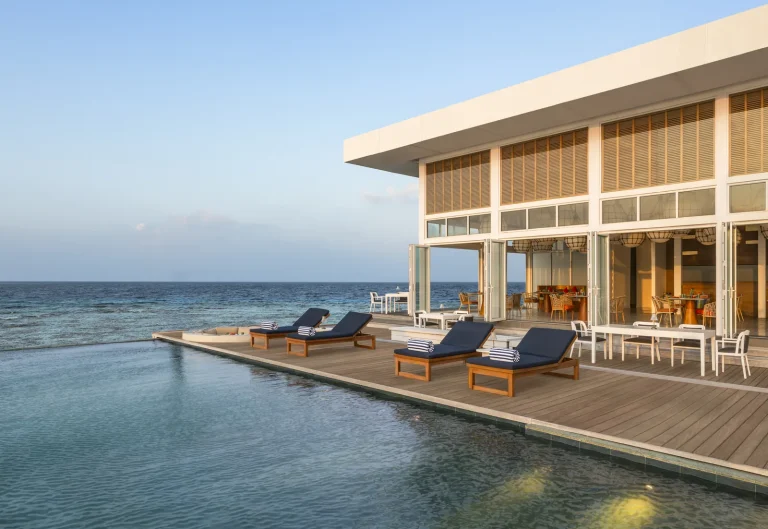 Overwater bar and pool deck with loungers at sunset at Yapa Bar, The Halcyon Private Isles Maldives