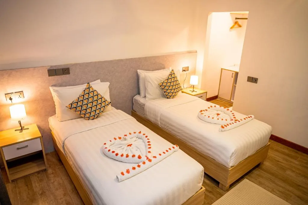 Hotel room with two beds with a cake on them at Holiday Crib, Dhiffushi, Maldives