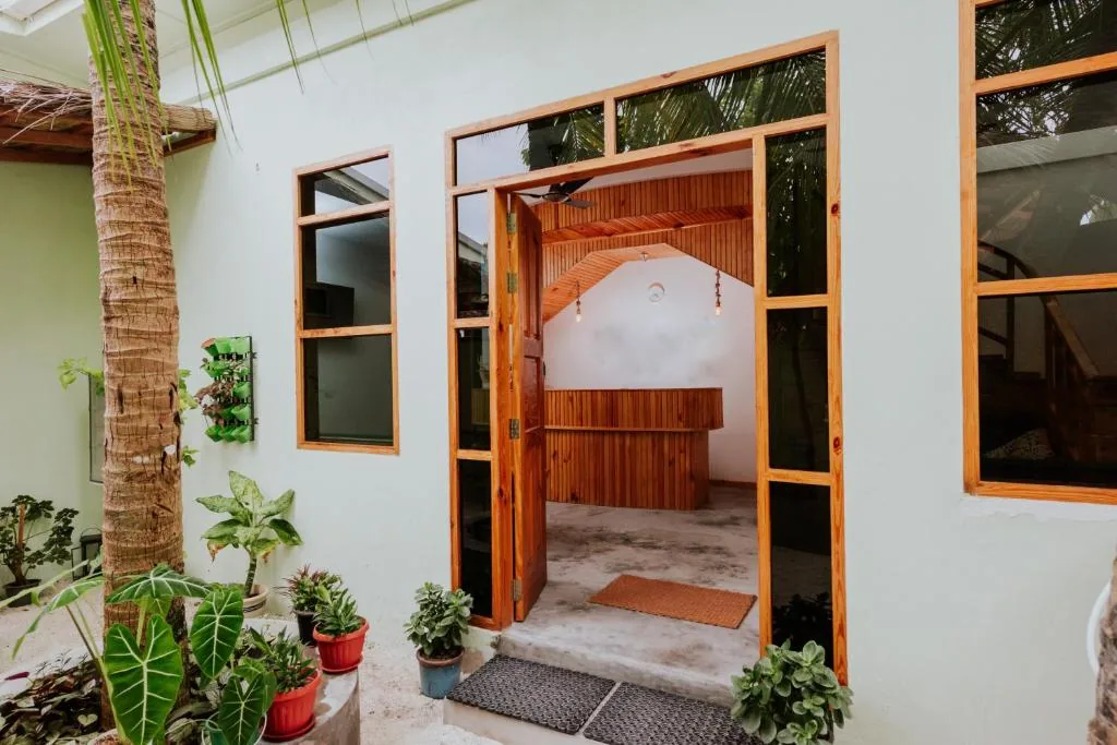 Open wooden reception desk with glass-block windows, hanging lights and potted plants in a tropical courtyard at Isla Dhiffushi, Dhiffushi, Maldives