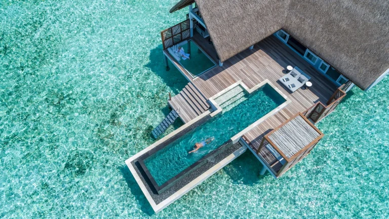 Aerial view of a water villa with a long private pool at Four Seasons Landaa Giraavaru, Baa Atoll