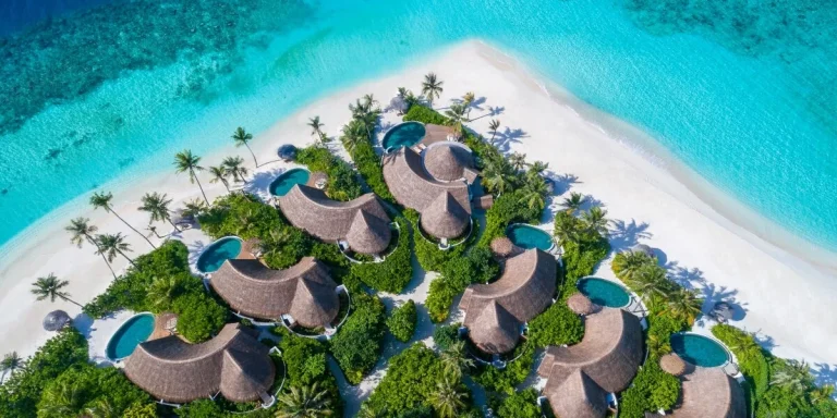 Aerial view of the thatched beach pool villas and white sand at Milaidhoo Maldives, Baa Atoll