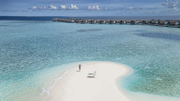 Couple on a sandbank in a turquoise lagoon near Four Seasons Landaa Giraavaru, Baa Atoll