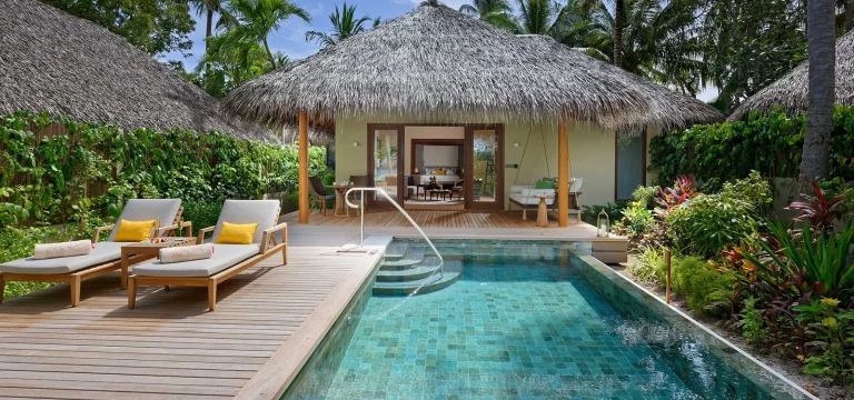 Thatched Baros Pool Villa with a private pool, deck and loungers in a tropical garden behind the beach, North MalΓ© Atoll, Maldives