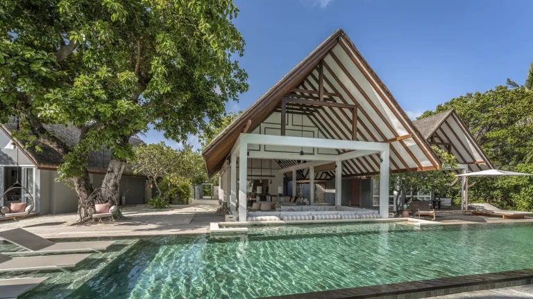 Beach villa with a long lap pool, timber deck and high pitched roof among trees at Four Seasons Resort Maldives at Landaa Giraavaru, Baa Atoll