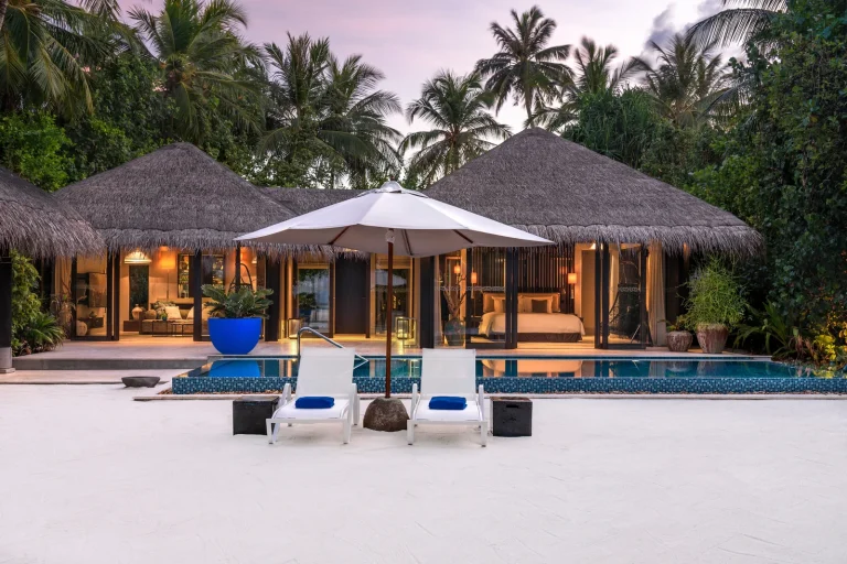 Deluxe Beach Pool Villa with a blue private pool, loungers and thatched pavilions on the sand at Velaa Private Island, Noonu Atoll