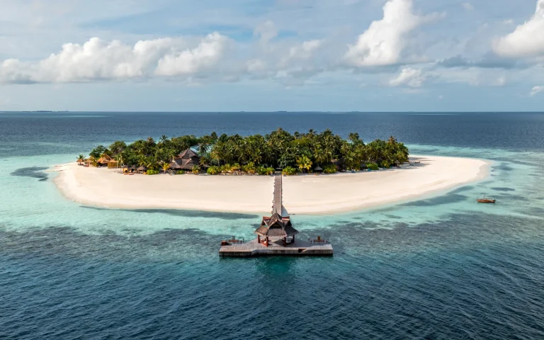 Aerial view of the small round island of Banyan Tree Vabbinfaru with its jetty and ring of white beach, North MalΓ© Atoll, Maldives
