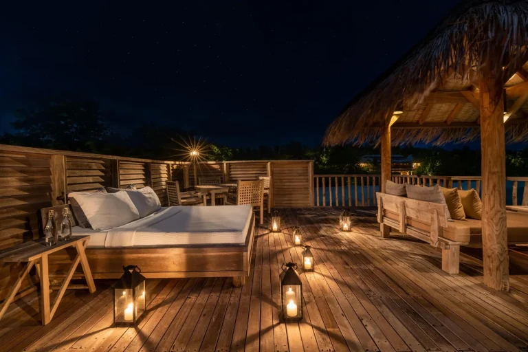 Lantern-lit rooftop daybed on an overwater villa deck at night at Gili Lankanfushi, North MalΓ© Atoll, Maldives