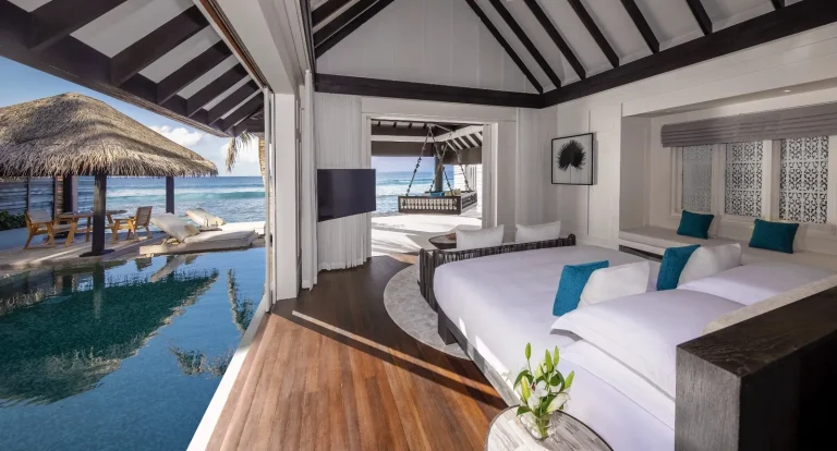 Bedroom of a Naladhu Ocean House opening onto a private pool and the lagoon, South MalΓ© Atoll, Maldives