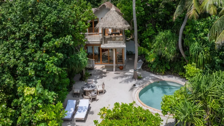 Aerial view of a two-storey thatched Crusoe villa with a round private pool and hammock in thick jungle at Soneva Fushi, Baa Atoll, Maldives