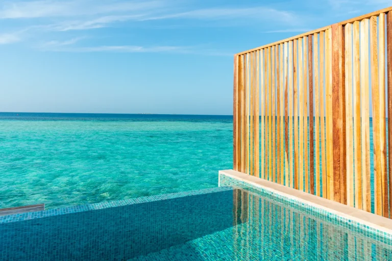 Private infinity pool on the deck of an overwater villa looking out over a turquoise lagoon and open sea, Cora Cora Maldives