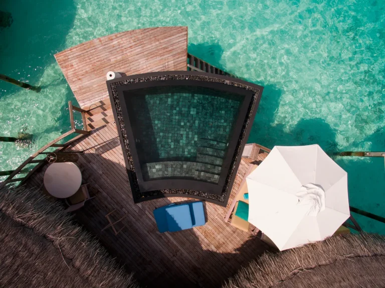 Top-down view of a water villa sundeck with a plunge pool, umbrella and loungers over the lagoon at Constance Halaveli, North Ari Atoll, Maldives
