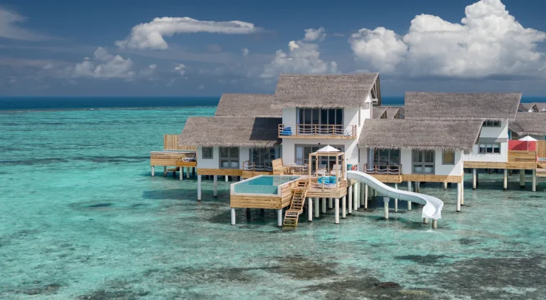 Aerial view of a two-bedroom overwater lagoon villa with a pool and a white water slide into the lagoon at Cora Cora Maldives, Raa Atoll
