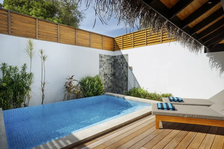 Private pool and sun deck of a beach villa enclosed by white walls and greenery at Niva Velassaru Maldives, South MalΓ© Atoll