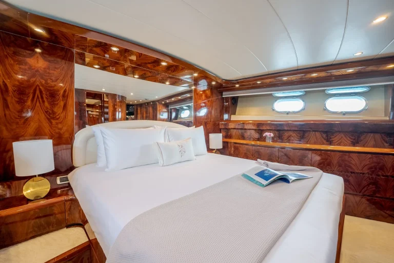 Master cabin with a large white bed and polished timber walls on a motor yacht, JOALI Maldives