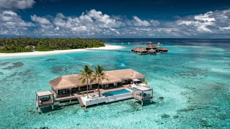Aerial view of the Romantic Pool Residence at Velaa Private Island, a single overwater villa with a long pool deck standing alone in the Noonu Atoll lagoon
