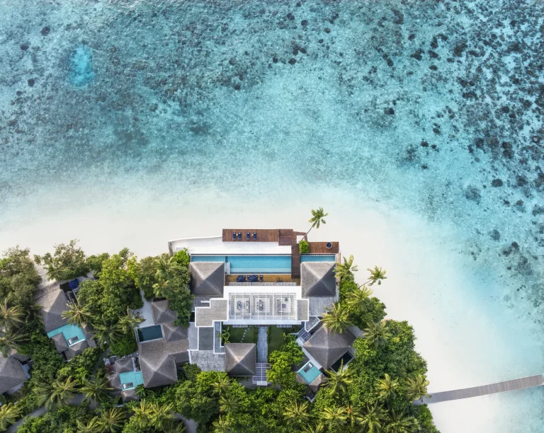 Aerial view of The Halcyon Grand Estate, a large white villa with pools set among trees above a turquoise lagoon, Gaafu Alifu Atoll, Maldives