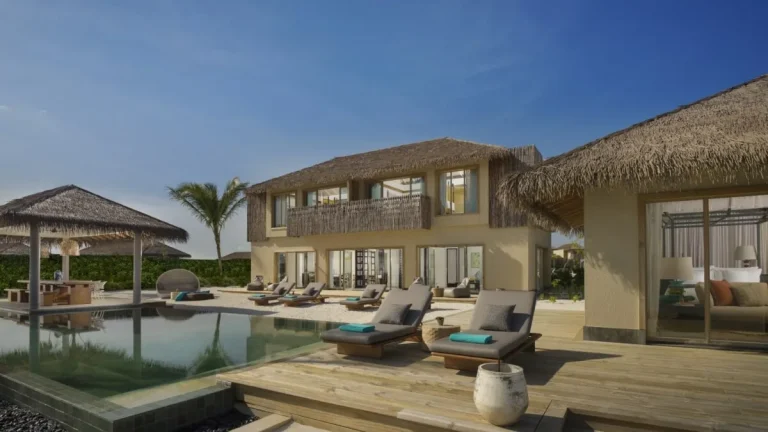 Two-storey thatched three-bedroom lagoon residence with an infinity pool and sun loungers at InterContinental Maldives Maamunagau, Raa Atoll