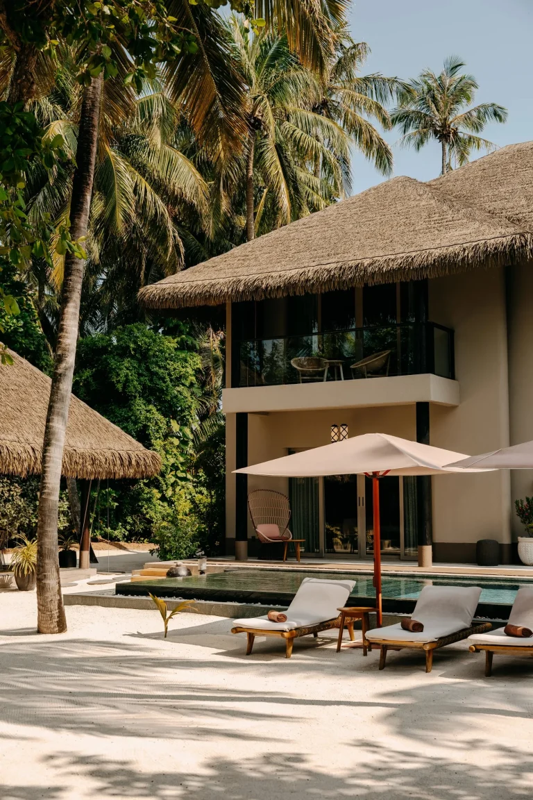 Two-storey thatched four-bedroom beach residence with a terrace and parasols among palms at JOALI Maldives, Raa Atoll