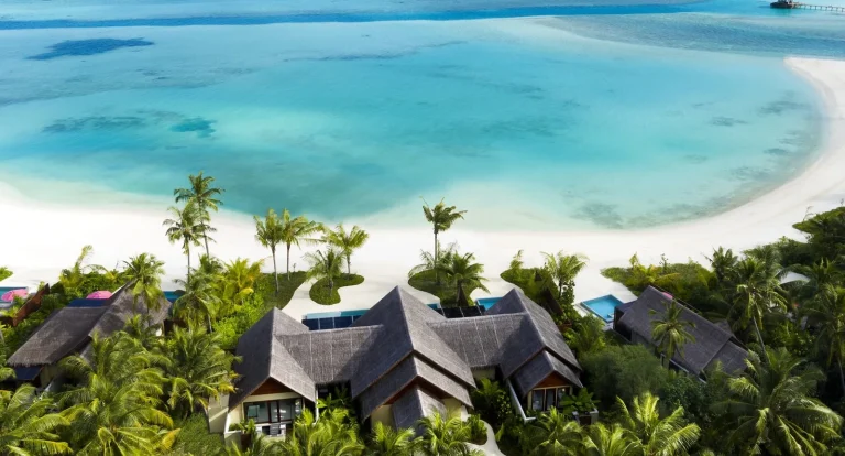 Aerial view of thatched multi-bedroom Beach Pool Pavilions among palms beside a white beach at Niyama Private Islands, Dhaalu Atoll, Maldives