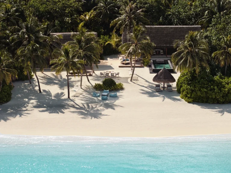 Aerial view of two thatched beach villas joined by a shared pool and lounge area on a white beach at One&Only Reethi Rah, North MalΓ© Atoll