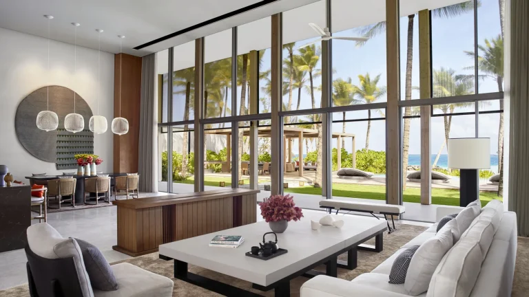 Double-height living room with floor-to-ceiling glass opening onto the garden and beach at The Ritz-Carlton Estate, Fari Islands, North MalΓ© Atoll
