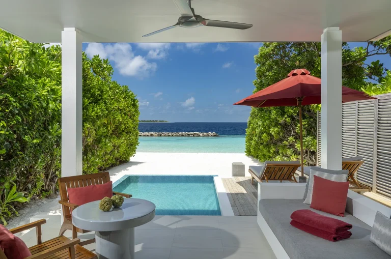 Covered terrace with red cushions and a plunge pool looking out to the beach and lagoon at a Beach Villa with Pool, Niva Dhigali Maldives