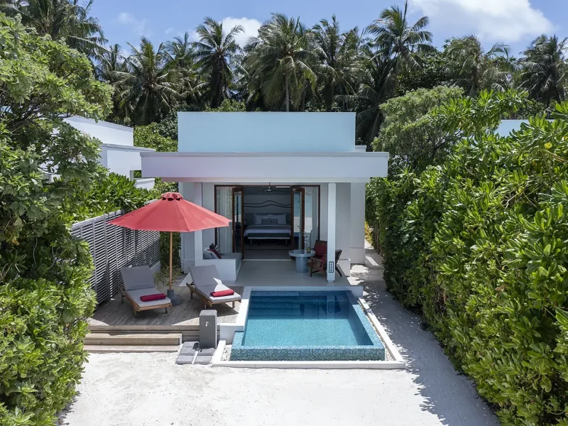 White modern villa with a private pool, red umbrella and loungers surrounded by palms, Niva Dhigali Maldives