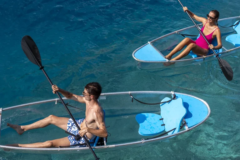 Two people paddling transparent kayaks over clear turquoise water, Niva Dhigali Maldives