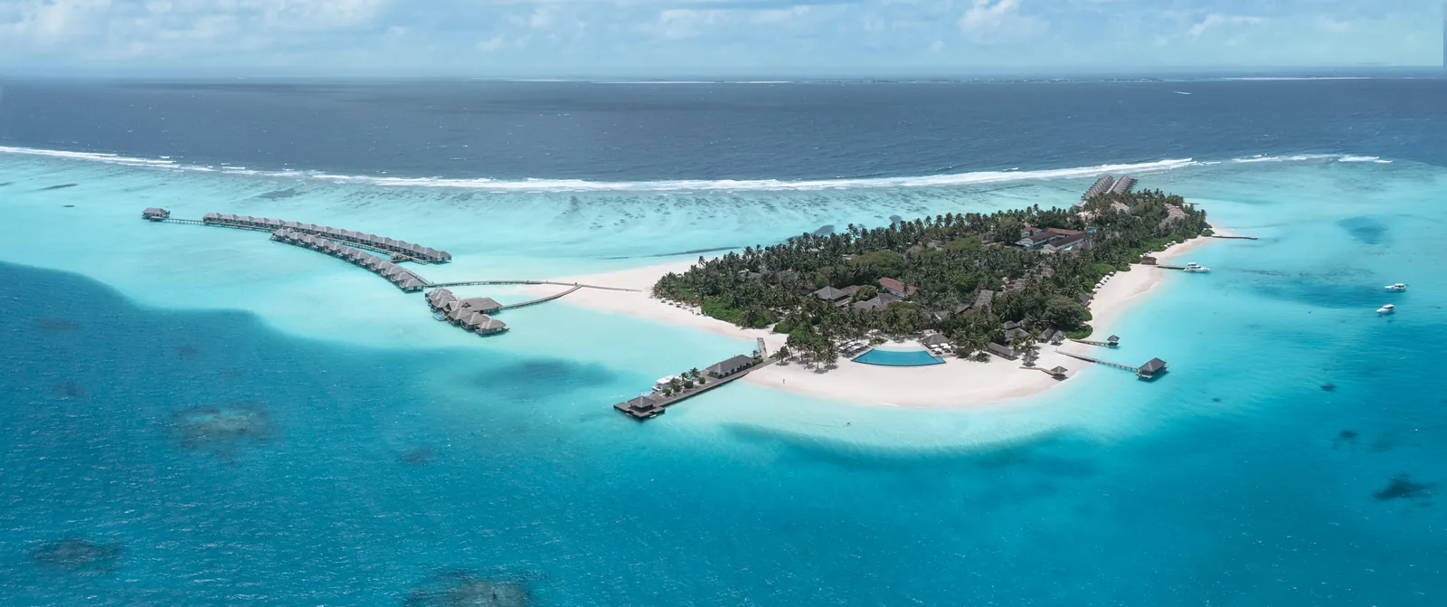 Aerial view of Velassaru island with its white beaches, wide turquoise lagoon and lines of overwater villas, South Malé Atoll, Maldives