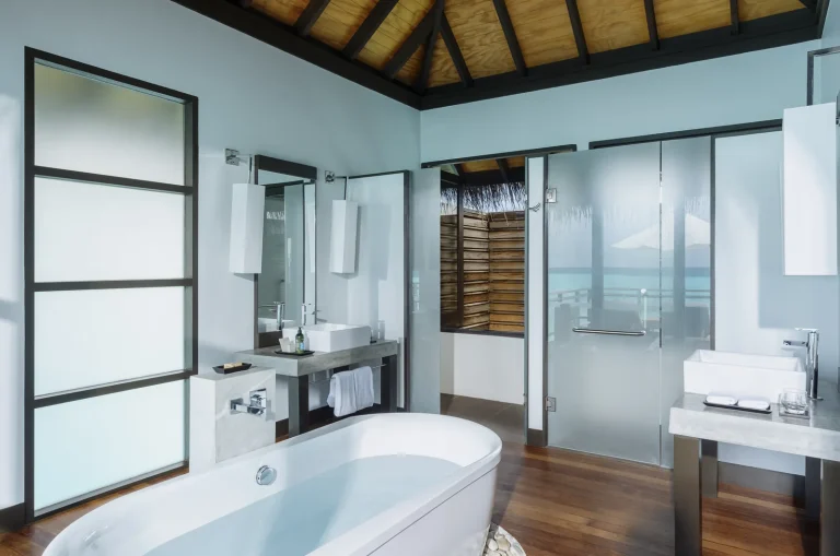Bright bathroom with a freestanding tub, twin basins and glass shower in a Water Villa with Pool, Niva Velassaru Maldives