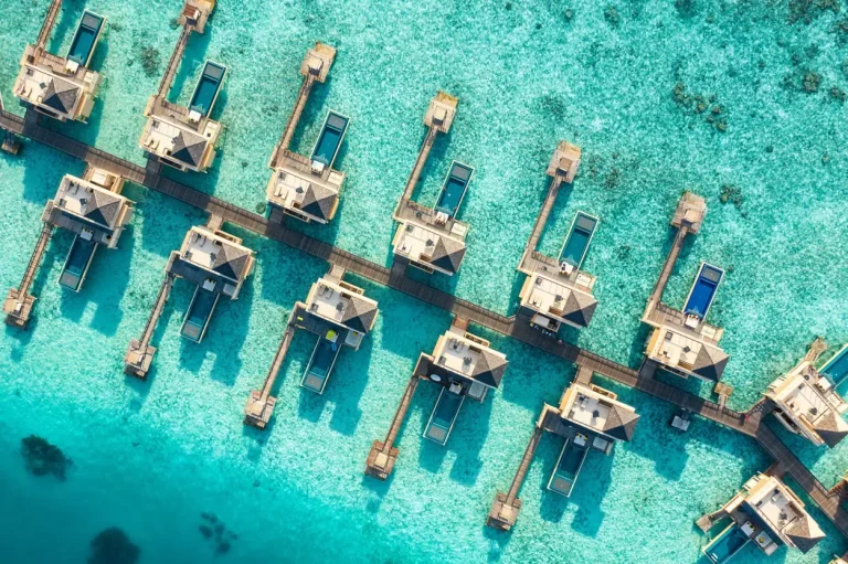 Aerial view of InOcean Pool Villas with private pools standing on stilts in the open lagoon at Angsana Velavaru, Dhaalu Atoll, Maldives