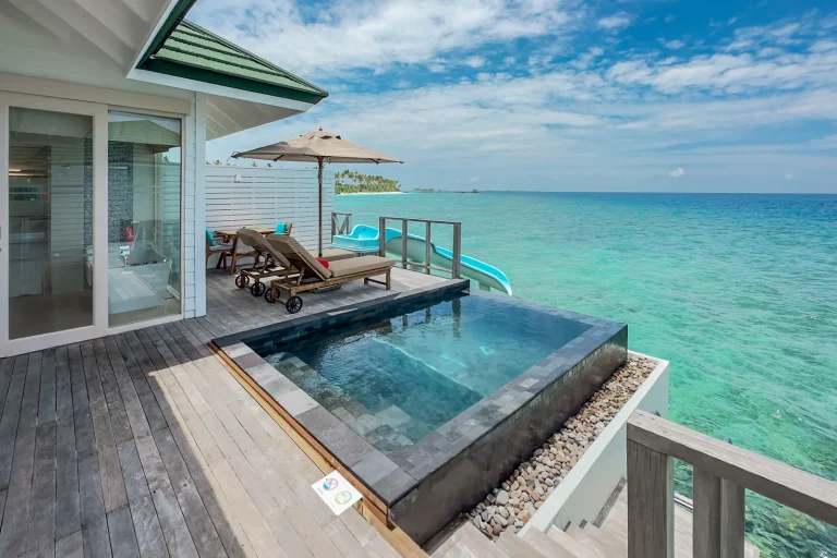 Overwater villa deck with an infinity plunge pool, loungers and a slide down to the lagoon at Siyam World Maldives, Noonu Atoll
