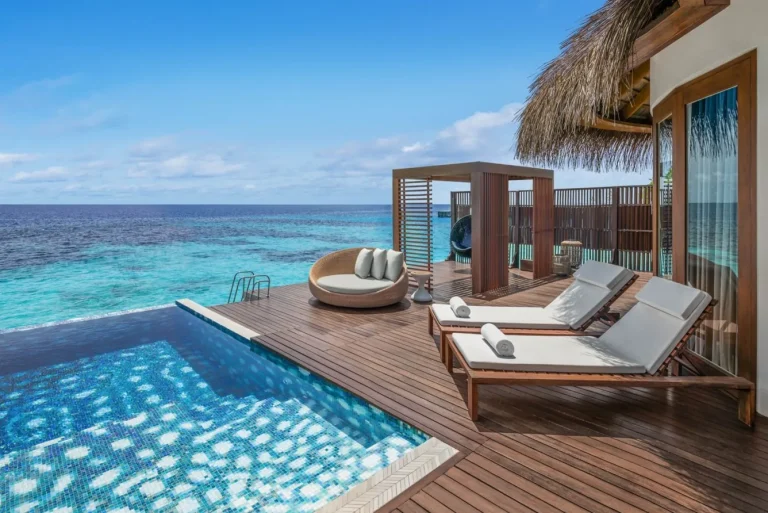Overwater villa terrace with a plunge pool, cabana and loungers above clear reef water at W Maldives, North Ari Atoll